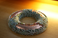 Ein Ring, teilweise mit weißen Elementen verziert, die freien Stellen sind mit bronzefarbener Farbe gestaltet.