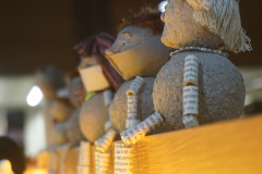 Figuren aus Papier und Pappmaché sitzen auf der Kante über der Balustrade.
