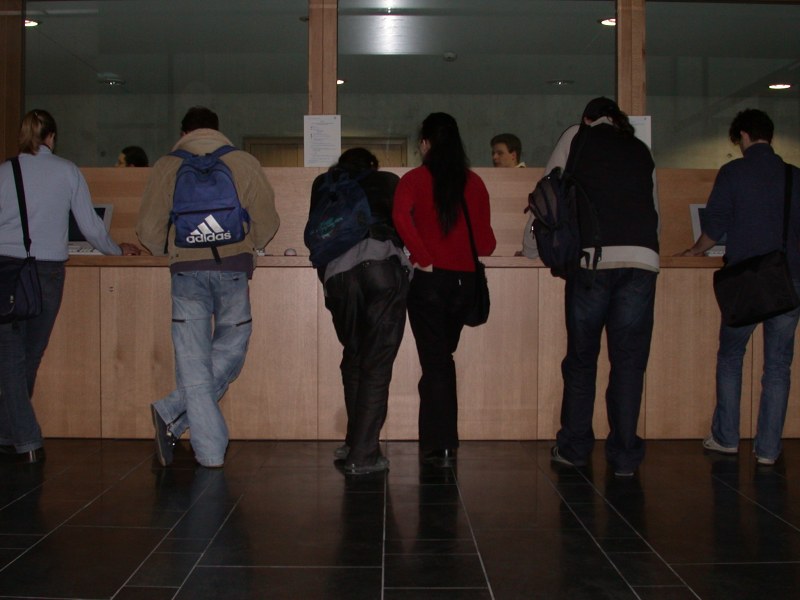 An den Rechnern im Foyer stehen Studierende, teilweise zu zweit.