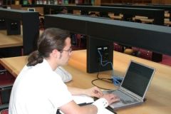 Ein Leser hat seinen Laptop mit einem LAN-Kabel an einer Netzwerkdose an den Tischen im Lesesaal angeschlossen