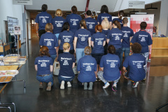 Gruppenbild, die Mitarbeiter:innen stehen mit dem Rücken zur Kamera, auf den dunkelblauen Shirts sind weiße Signaturen und Stichwörter aufgedruckt. Foto: CC BY UB der HU